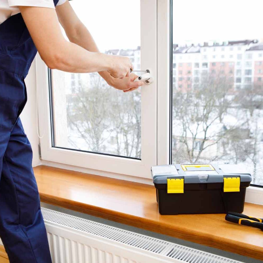 Håndverker som monterer eller reparerer en hvit vindusramme.