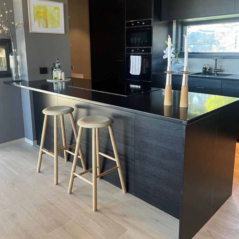 Moderne svart kjøkkenøy med to barkrakker i tre.